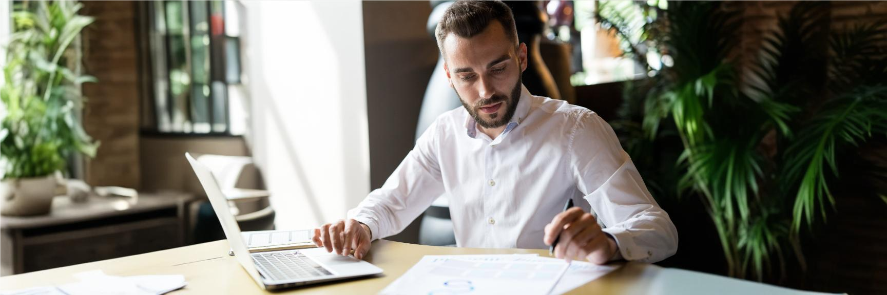 Contador sentado à mesa, utilizando de ferramentas digitais como um notebook para realizar suas tarefas